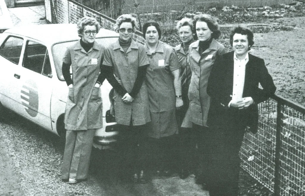 Historisk sort-hvidt foto af Peer og fem rengøringsmedarbejdere ved en firmabil