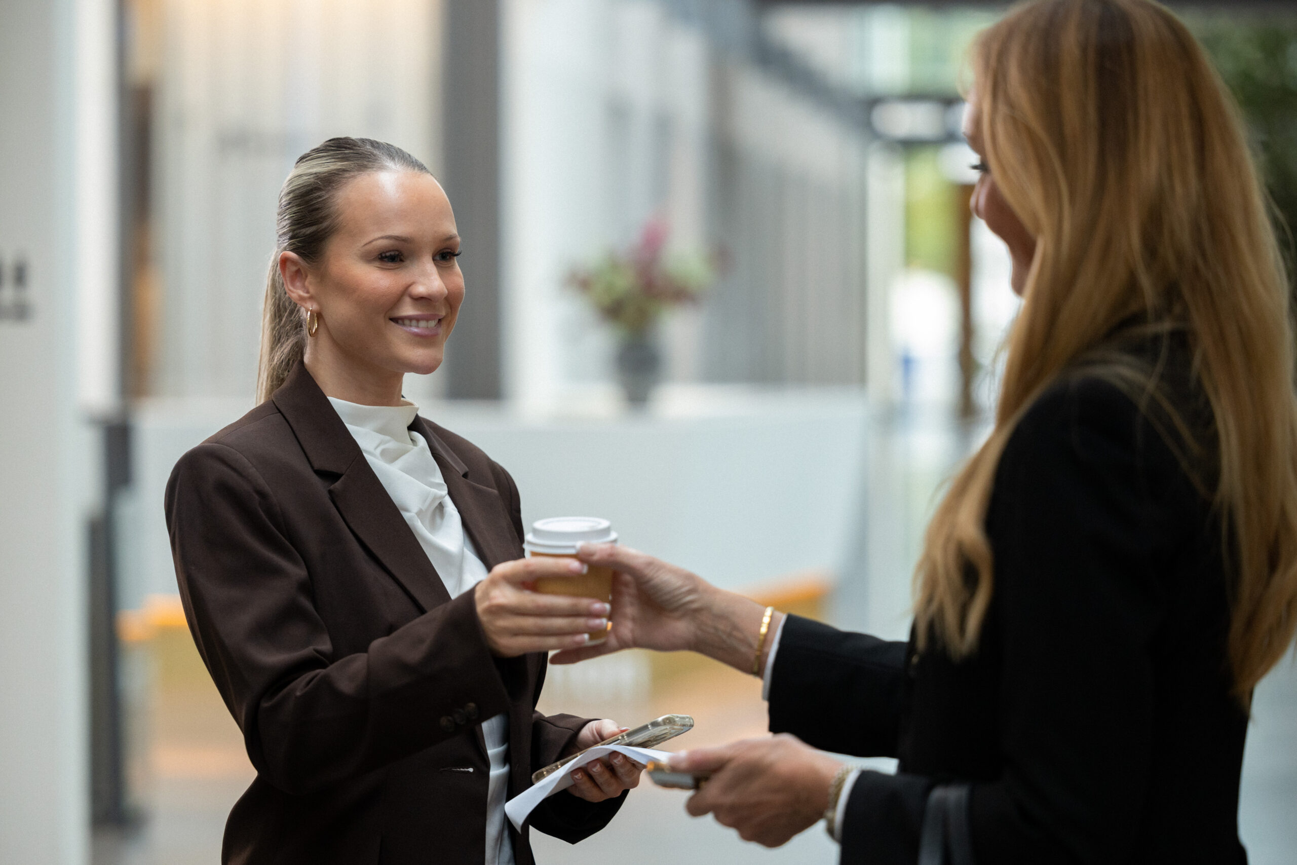 Receptionist rækker en kop kaffe til en gæst