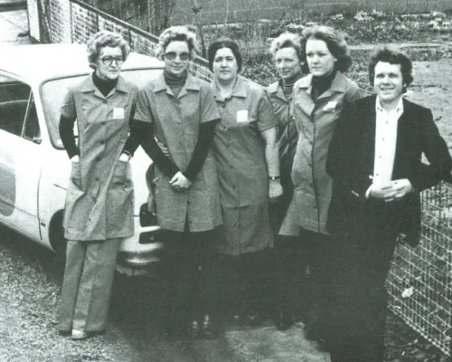 Historisk sort-hvidt foto af Peer og fem rengøringsmedarbejdere ved en firmabil